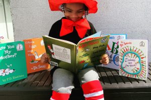 Child reading with books around them